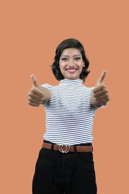 Mujer bonita sonriente llena de alegría mostrando los pulgares hacia