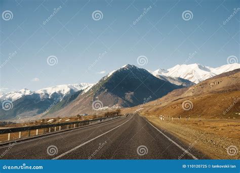 View Of The Autumn Road Leading To The Mountains To The Snow Capped