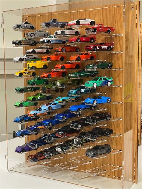 A Wooden Display Case Filled With Lots Of Toy Cars On Top Of A White Table