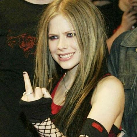 A Woman With Long Hair And Gloves Making The Peace Sign While Standing