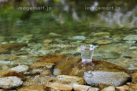 綺麗な川に置かれた水の入ったグラスの写真素材 [193344550] イメージマート