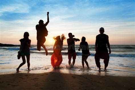 Six Personnes Sautant Sur La Plage Au Coucher Du Soleil Image Stock