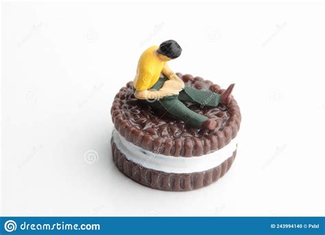 Estatuilla En Miniatura De Un Hombre Sentado Sobre Una Galleta Gigante