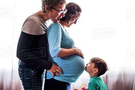 Lesbian Couple With Son Standing By Window Stock Photo Dissolve