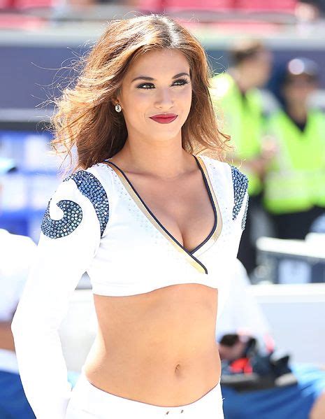 A Woman In White Is Posing For The Camera At A Football Game With Her