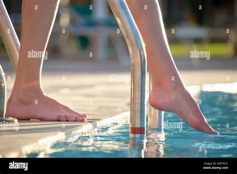 Closeup Of Woman Legs Entering Swimming Pool Water In Summer Resort Tropical Vacation Concept