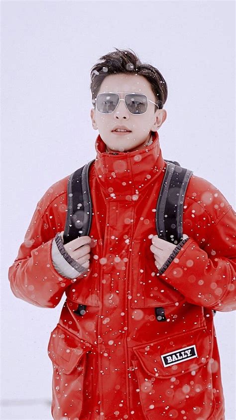 A Man In Red Jacket And Sunglasses Standing On Snow Covered Ground With