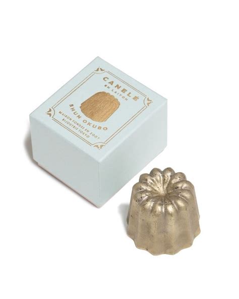 A Small White Box Next To A Gold Candle Holder On A White Surface With