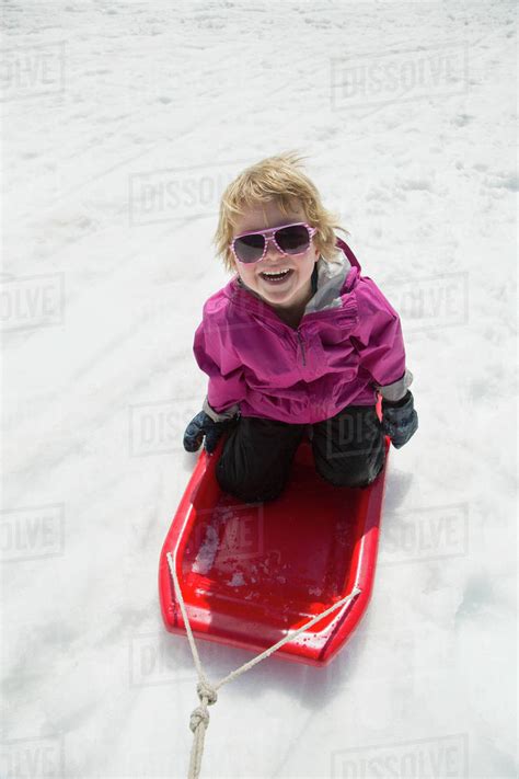 High Angle View Of Cheerful Boy Tobogganing On Snow Covered Field