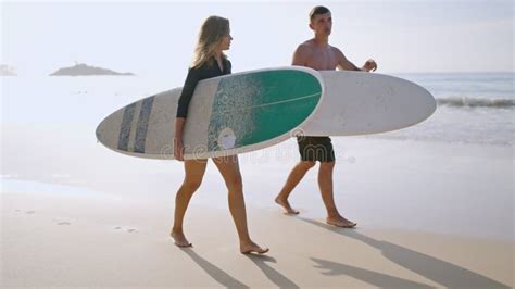 Aerial Top View Of Surfers Couple Walking On Sandy Beach With