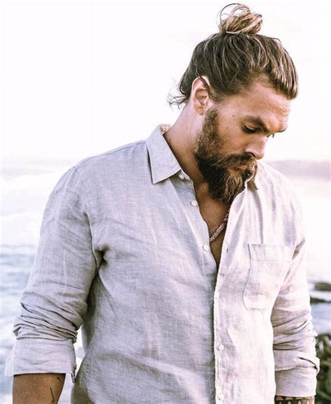 A Man With Long Hair And A Beard Standing Near The Ocean