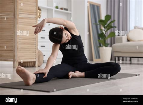 Girl Practicing Revolved Head To Knee Asana On Yoga Mat At Home