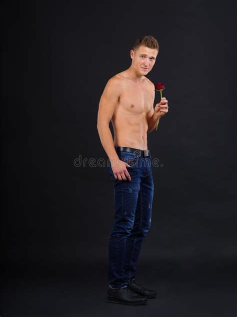 A Guy With A Naked Torso Holds A Rose In His Hand Building Sideways