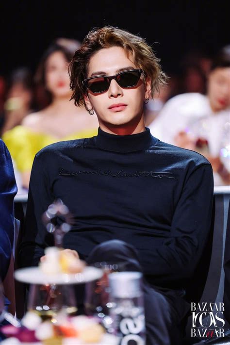 A Man Wearing Sunglasses Sitting In Front Of A Crowd