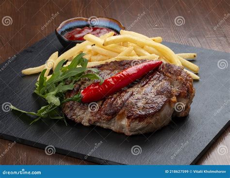 Bife De Porco Batatas Fritas E Molho Vermelho Numa Prancha De Pedra