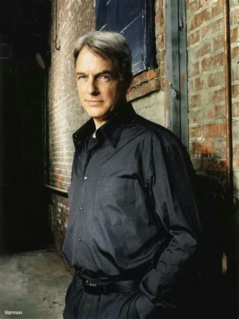 An Older Man Standing In Front Of A Brick Building With His Hands On