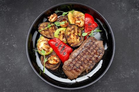 Premium Photo Meat Steak With Grilled Vegetables On A Dark Plate