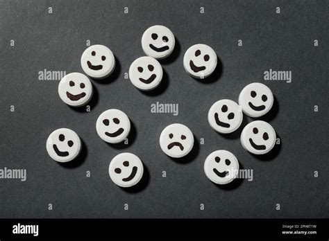 Pill with sad face among happy ones on black background, flat lay ... 