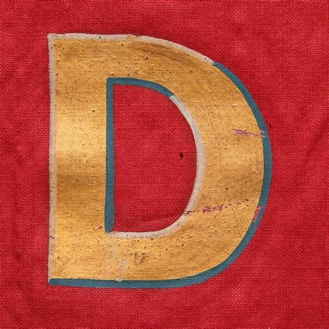 Gold and Blue Paint Letter D on Red Cloth Background