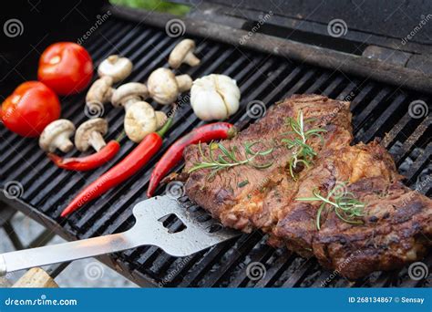 Beef Steaks Cooking On The Charcoal Grill With Chili Pepper Tomatoes