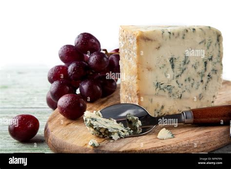 Stilton On A Cheese Board With Red Grapes And Cheese Spoon Stock Photo