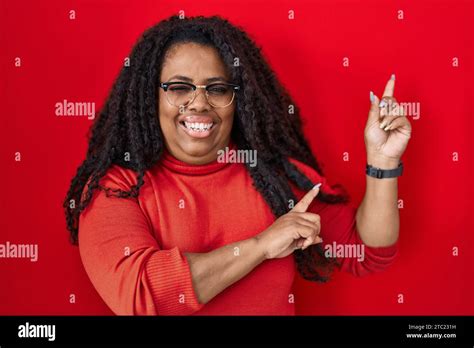 Plus Size Hispanic Woman Standing Over Red Background Smiling And Looking At The Camera Pointing