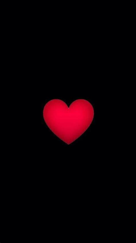 A Red Heart In The Middle Of A Black Background With Only One Light On It