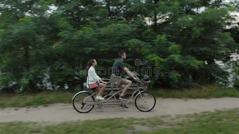 Married Couple With A Child Rides A Two Person Tandem Bike Along The