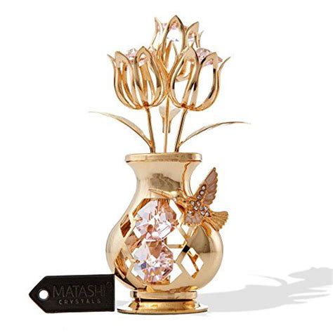 A Gold Vase With Flowers And A Butterfly On The Top Sitting In Front