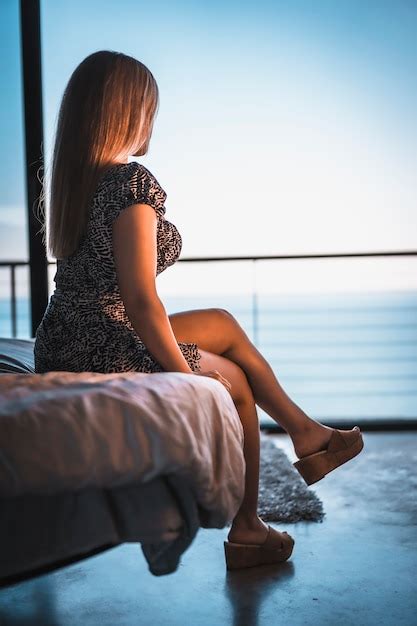 Jeune Femme Blonde De Race Blanche Dans Une Courte Robe Noire Et Blanche Assise Sur Le Lit Du