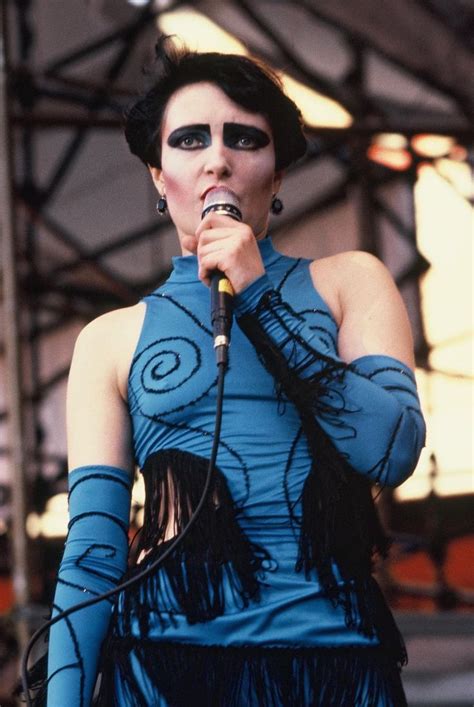 A Woman In Blue Dress Holding A Microphone And Wearing Black Eye Make