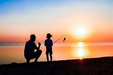 Um pai feliz e pescadores infantis pegam peixes à beira mar em viagens