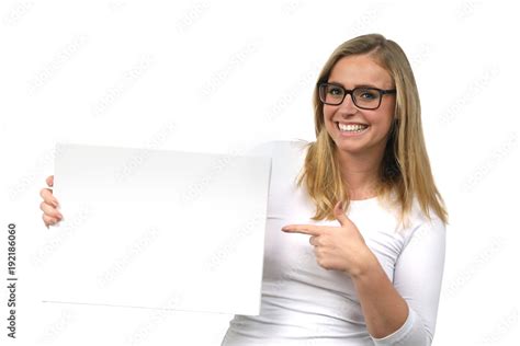 Hübsche blonde Frau mit brille lacht und zeigt auf eine leere Tafel in ihren Händen Stock Photo