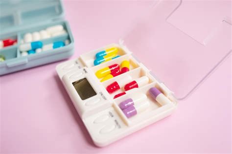 Una Caja De Medicamentos Con Diferentes Pastillas Sobre Un Fondo Rosa