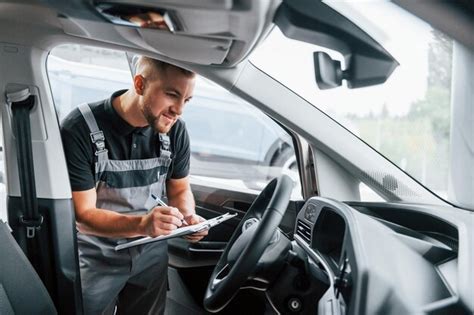 Mirando dentro del auto el hombre en uniforme está trabajando en el