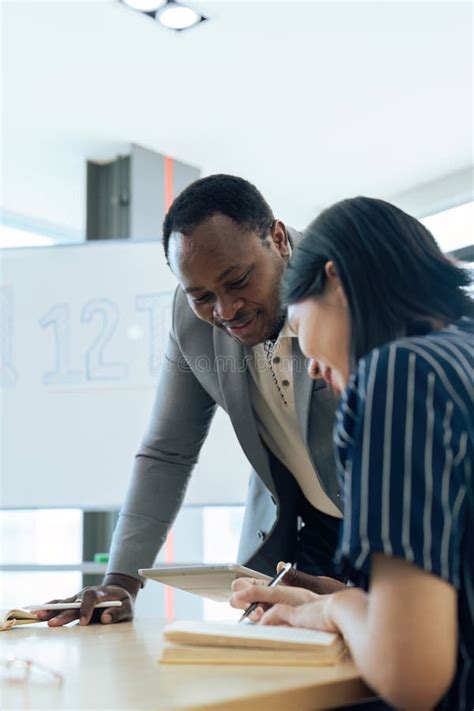 Mature Professor Talking To His Student While Assisting Her On A Class
