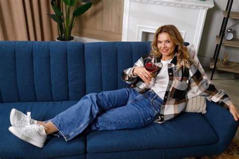 Premium Photo Satisfied Mature Woman Drinking Wine On The Sofa In The Living Room
