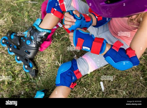 Overhead View Of Little Girl Putting On Safety Gear For Inline Skating