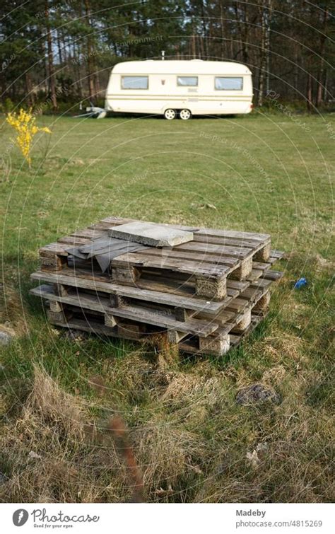 Gestapelte Europaletten aus Holz auf grünem Rasen im Frühling mit