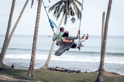 Young Couple Swinging On The Tropical Beach Of Bali Island Indonesia