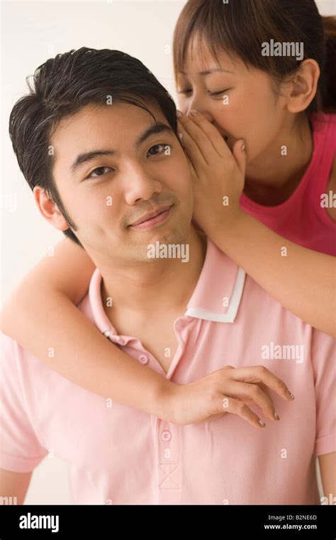 Close Up Of A Young Woman Whispering Into A Young Mans Ear Stock Photo