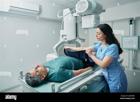 Female Technician Preparing Patient For Body X Ray In Radiographic