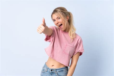 Blonde frau über isolierter blauer wand mit daumen hoch weil etwas gutes passiert ist Premium