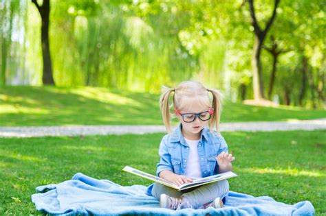 Une Jolie Petite Fille Blonde Avec Des Cheveux Blonds Et Des Lunettes De Lecture En Lisant Un