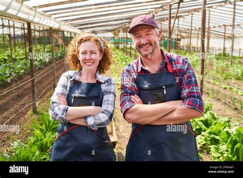 Portrait Of Smiling Mature Male And Female Farmers Standing With Arms