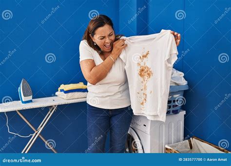 Middle Age Hispanic Woman Putting Dirty Laundry Into Washing Machine