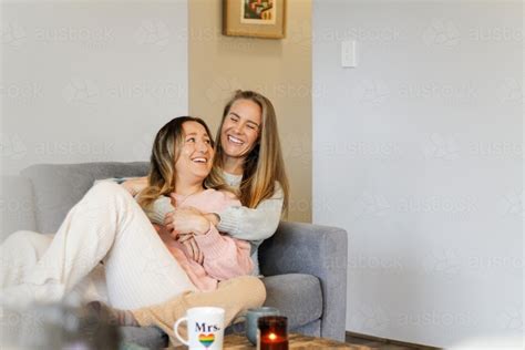 Image Of A Lesbian Couple Laughing Talking And Hugging On The Couch