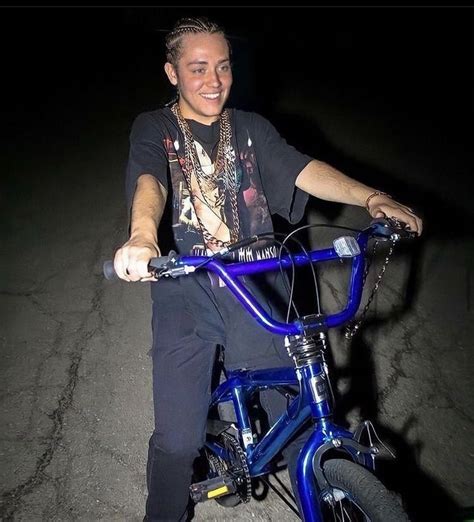 A Man Sitting On Top Of A Blue Bike In The Dark With His Hand On The Handlebars