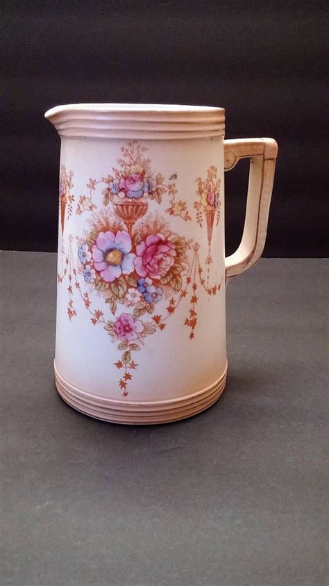 A White And Pink Flowered Pitcher Sitting On Top Of A Gray Countertop