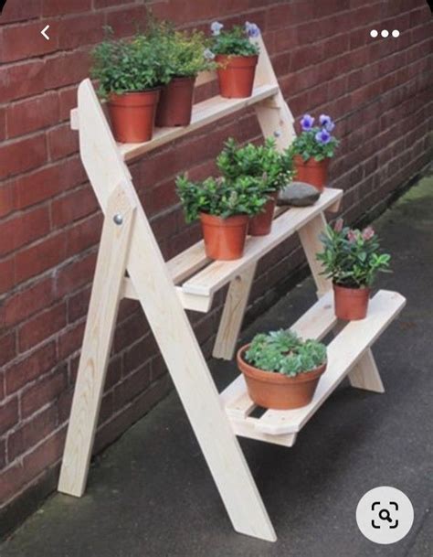 Several Potted Plants Are Placed On A Wooden Ladder Next To A Brick